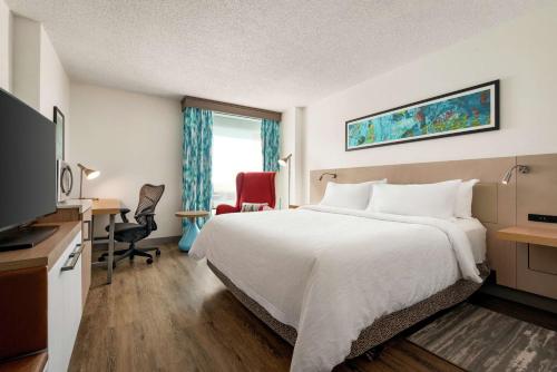 a hotel room with a bed and a desk and a television at Hilton Garden Inn Saskatoon Downtown in Saskatoon
