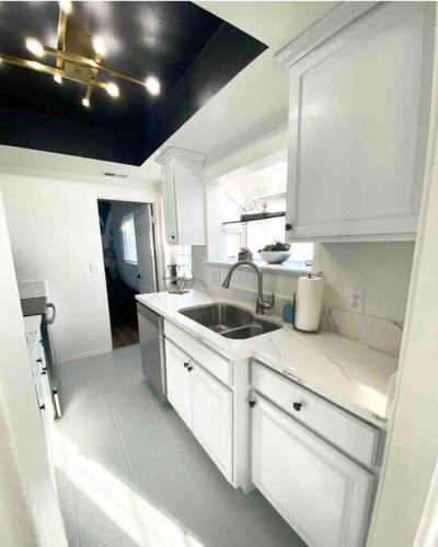 a kitchen with white cabinets and a sink at Crown Point Home w/ Cowboy Pool 2 Blocks to Bay in San Diego