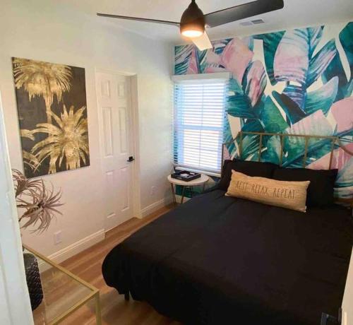 a bedroom with a black bed with a tropical mural at Crown Point Home w/ Cowboy Pool 2 Blocks to Bay in San Diego
