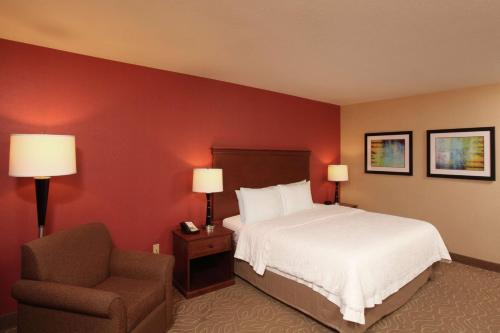 a hotel room with a bed and a chair at Hampton Inn Spokane Airport in Spokane