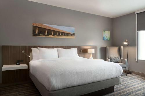 a bedroom with a large white bed and a chair at Hilton Garden Inn Lompoc, Ca in Lompoc