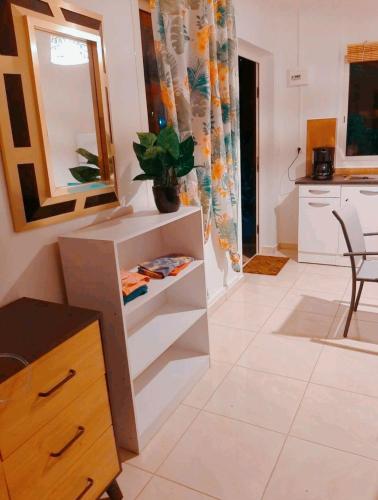 a kitchen and living room with a table and a mirror at Logement cosy cadre tropical, arbres fruitiers in Les Abymes