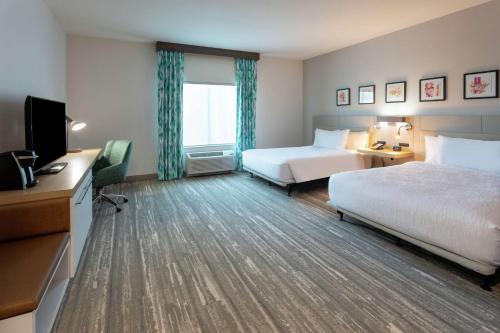 a hotel room with two beds and a flat screen tv at Hilton Garden Inn St. Cloud, Mn in Waite Park