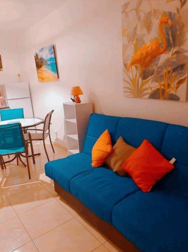 a blue couch in a living room with a table at Logement cosy cadre tropical, arbres fruitiers in Les Abymes