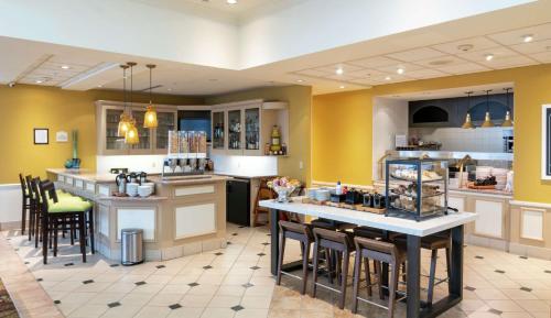 a kitchen with yellow walls and tables and chairs at Hilton Garden Inn Wooster in Wooster