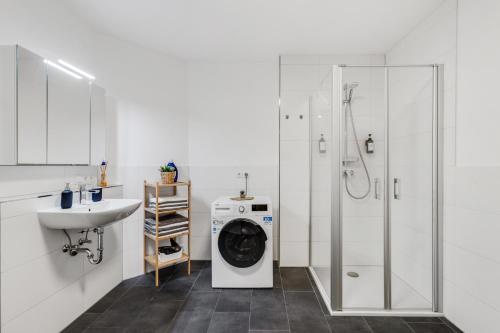 een witte badkamer met een wasmachine en een wastafel bij WINETIME - modern - Boxspringbetten - Netflix - Nähe Mercedes-Benz in Wörth am Rhein