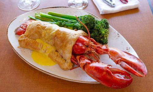 a plate of food with lobster and vegetables on a table at Hilton Chicago/Northbrook in Northbrook