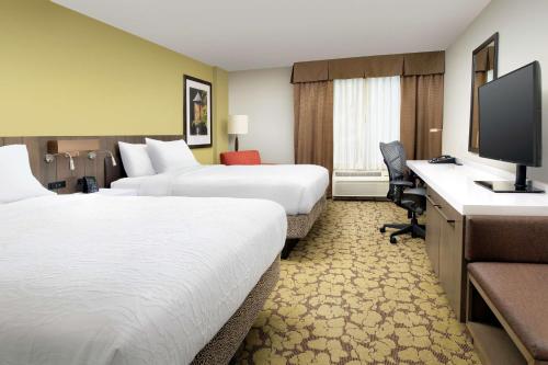 a hotel room with two beds and a desk with a computer at Hilton Garden Inn Frederick in Frederick