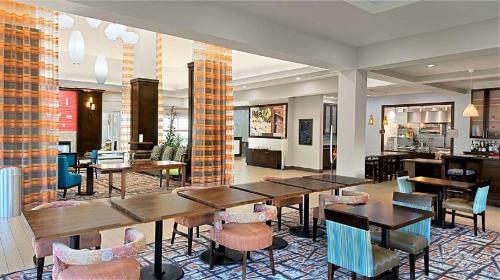 a restaurant with tables and chairs in a room at Hilton Garden Inn Houston Cypress Station in Westfield