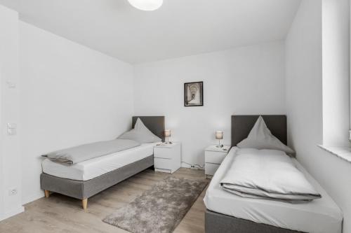 2 Betten in einem Zimmer mit weißen Wänden und Holzböden in der Unterkunft WINETIME - modern - Boxspringbetten - Nähe Mercedes-Benz in Wörth am Rhein