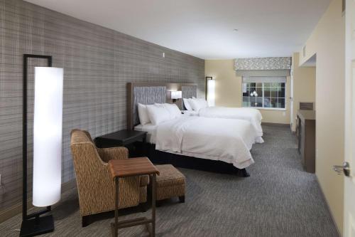 duży pokój hotelowy z 2 łóżkami i krzesłem w obiekcie Hampton Inn Holland w mieście Holland