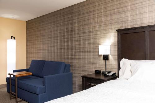 a bedroom with a blue chair next to a bed at Hampton Inn Holland in Holland