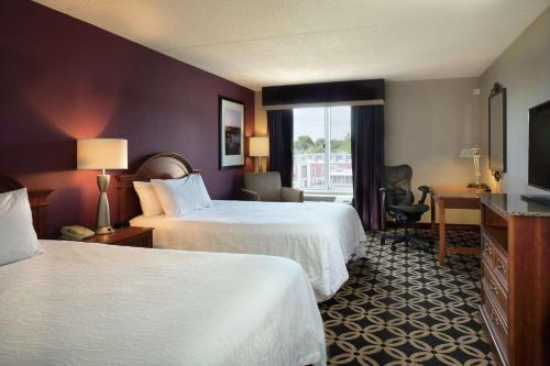 una camera d'albergo con due letti e una televisione di Hilton Garden Inn Auburn Riverwatch ad Auburn