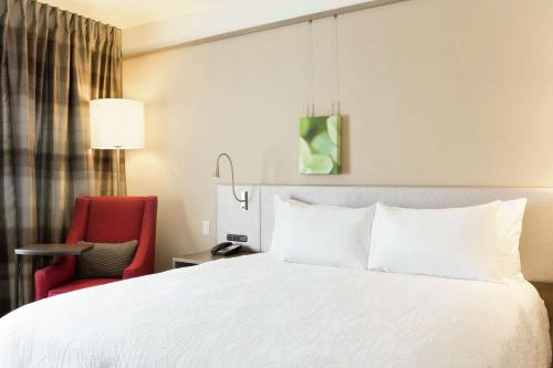 a bedroom with a white bed and a red chair at Hilton Garden Inn Pittsburgh Airport South-Robinson Mall in Robinson Township