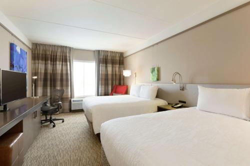 a hotel room with two beds and a flat screen tv at Hilton Garden Inn Pittsburgh Airport South-Robinson Mall in Robinson Township