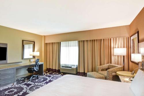 a hotel room with a bed and a chair and a television at Hilton Garden Inn Raleigh/Crabtree Valley in Raleigh