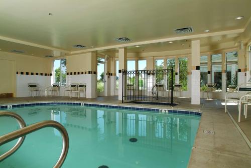 a large swimming pool with chairs and tables in a building at Hilton Garden Inn Tulsa Airport in Tulsa