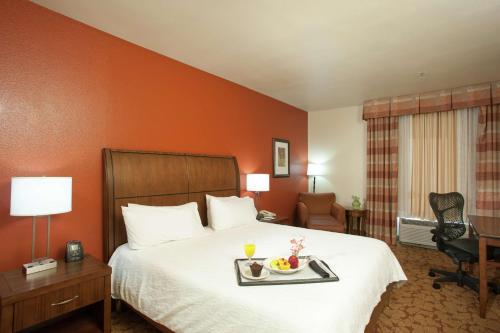 a hotel room with a bed with a tray of food on it at Hilton Garden Inn Tulsa Airport in Tulsa