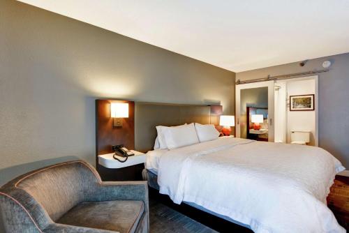 a hotel room with a large bed and a chair at Hampton Inn Cincinnati Airport South in Florence