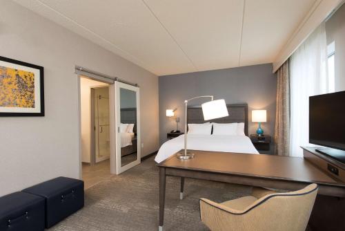 Cette chambre comprend un lit, un bureau et une télévision. dans l'établissement Hampton Inn & Suites Grand Rapids Downtown, à Grand Rapids