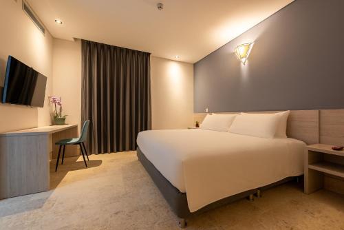 um quarto de hotel com uma cama, uma secretária e uma televisão em HOTEL RILUX CARTAGENA em Cartagena das Índias