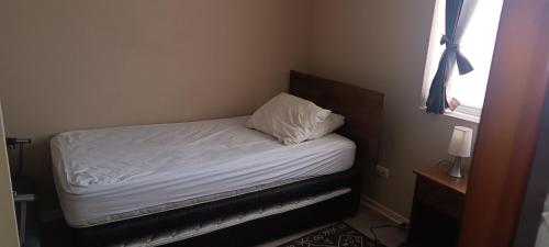 a small bedroom with a bed with white sheets and a window at Laguna Bahia Algarrobo in Algarrobo
