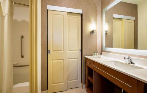 Homewood Suites by Hilton Winnipeg Airport - Polo Park في وينيبيغ: حمام مع حوض ومرحاض ومرآة