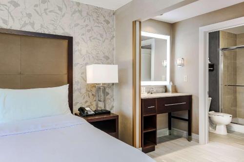a bedroom with a bed and a bathroom with a sink at Homewood Suites by Hilton Long Island-Melville in Plainview
