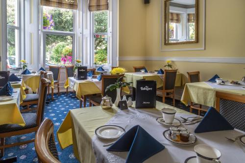 uma sala de jantar com mesas e cadeiras com guardanapos azuis em Balincourt em Bournemouth