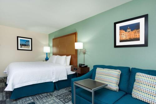 a hotel room with a bed and a blue couch at Hampton Inn Norcross in Norcross