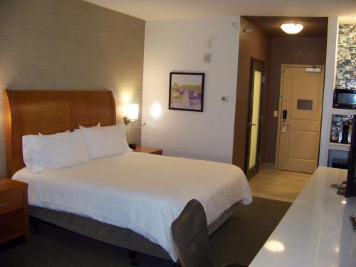 a hotel room with a large bed and a door at Hilton Garden Inn West Des Moines in West Des Moines