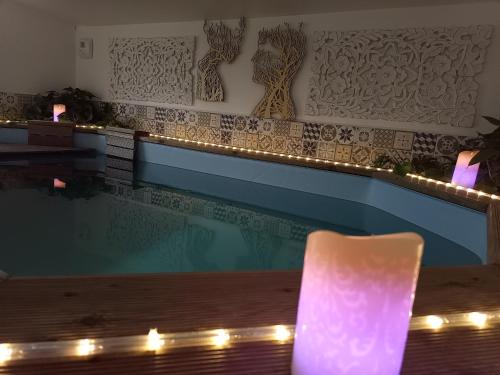 Studio de charme avec piscine de relaxation في Moyaux: حمام سباحة مع أضواء بجوار طاولة مع مصباح