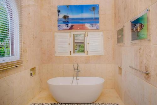a white tub in a bathroom with two windows at Sunny Vacation Villa No 93 in San Rafael del Yuma