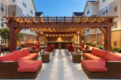an outdoor patio with red chairs and a wooden pergola at Homewood Suites Harrisburg-West Hershey Area in Mechanicsburg