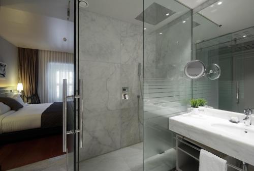 a bathroom with a shower and a sink and a bed at Preciados in Madrid