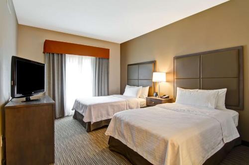 a hotel room with two beds and a flat screen tv at Homewood Suites Houston Kingwood Parc Airport Area in Kingwood