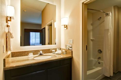 a bathroom with a sink and a mirror and a shower at Homewood Suites Houston Kingwood Parc Airport Area in Kingwood
