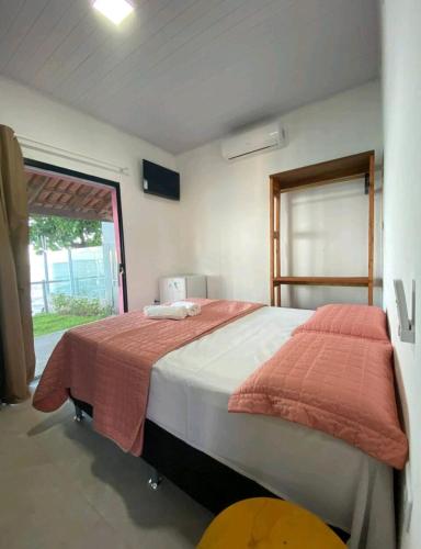 a bedroom with a large bed and a window at suítes Pataxós in Cumuruxatiba