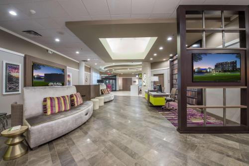 an office lobby with a couch and a tv at DoubleTree by Hilton Winston Salem - University, NC in Winston-Salem
