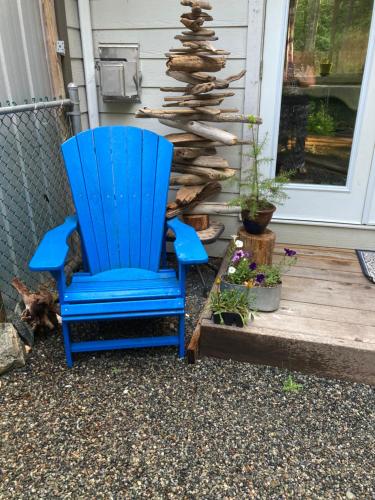 Studio suite retreat في Shawnigan Lake: كرسي هزاز أزرق جالس أمام منزل
