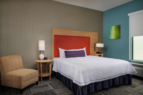 a bedroom with a large bed and a chair at Home2 Suites By Hilton Muskogee in Muskogee