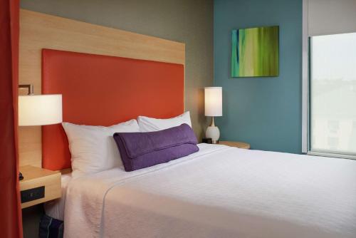 a bedroom with a large bed with a purple pillow at Home2 Suites By Hilton Muskogee in Muskogee