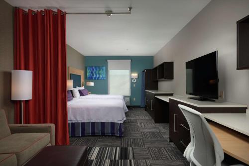a hotel room with a bed and a flat screen tv at Home2 Suites By Hilton Muskogee in Muskogee