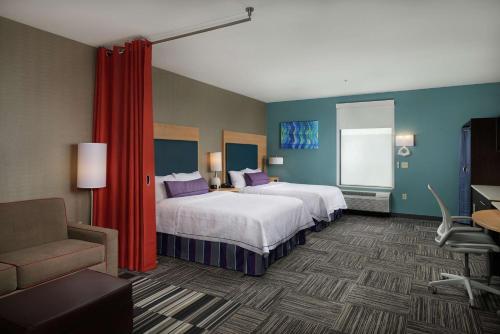 a hotel room with two beds and a chair at Home2 Suites By Hilton Muskogee in Muskogee