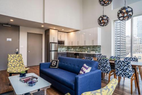 a living room with a blue couch and a kitchen at The Bernic Hotel New York City,Tapestry Collection by Hilton in New York
