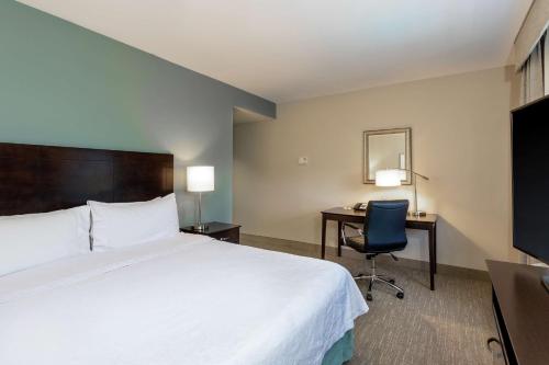 a hotel room with a bed and a desk and a chair at Homewood Suites Port Saint Lucie-Tradition in Port Saint Lucie