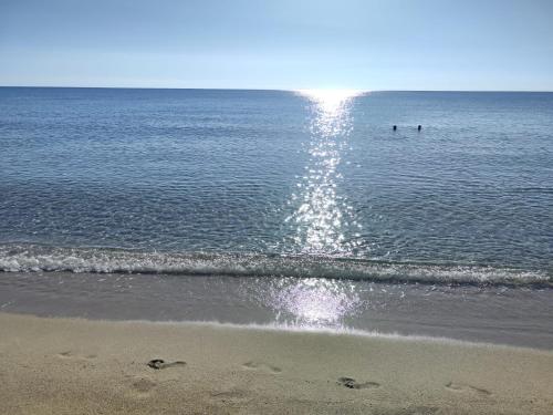 a beach with two people swimming in the ocean at Sunrise Sardinia Posada in Posada