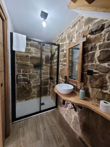 baño con ducha de cristal y pared de piedra. en Cabaña Pasiega Montes del Pas, 