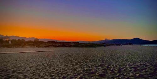 a sunset on a beach with mountains in the background at Sunrise Sardinia Posada in Posada