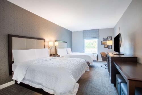 a hotel room with two beds and a flat screen tv at Hampton Inn Rochester Penfield, Ny in Penfield
